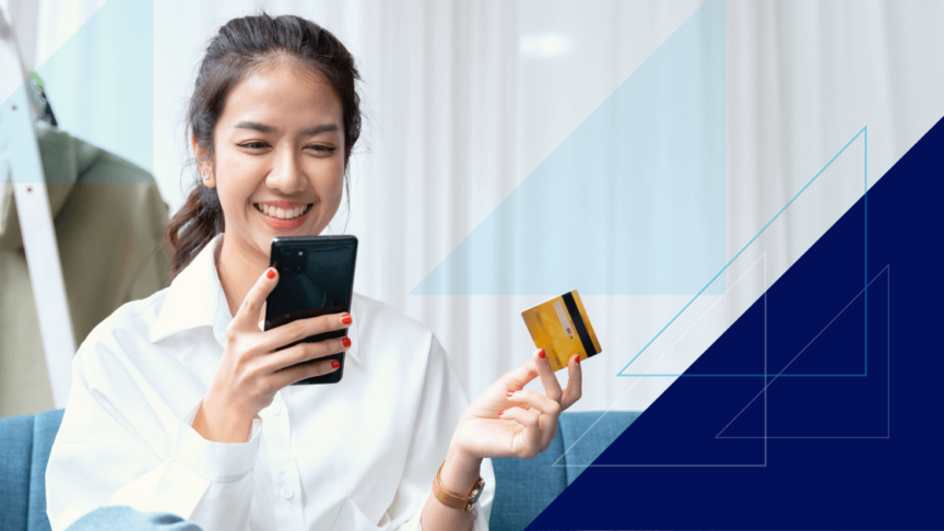 Woman smiling at cell phone while holding her credit card after using mobile wallet while online shopping