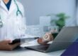Healthcare professional reviewing patient payment data and security risk information on connected digital systems